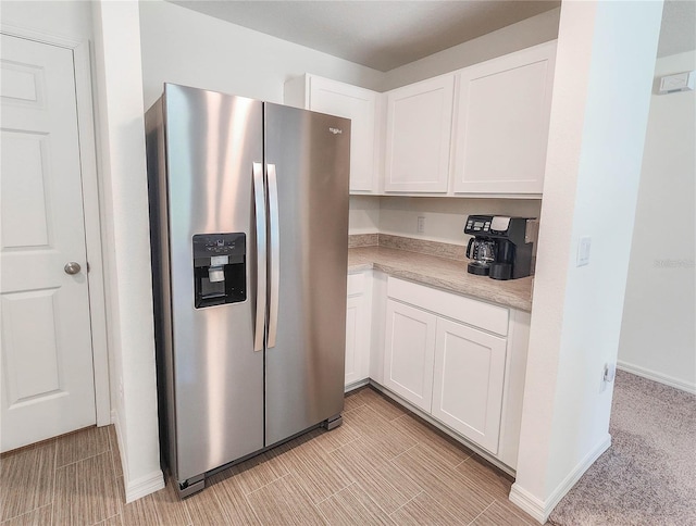 kitchen featuring stainless steel fridge with ice dispenser, white cabinets, and light carpet