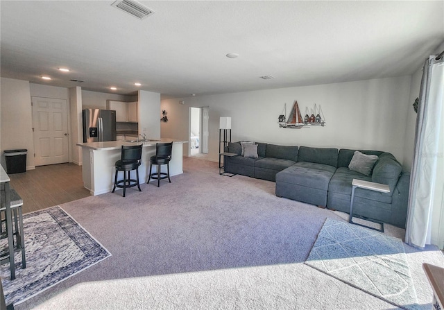 living room with light colored carpet and sink