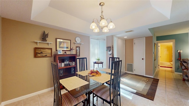 tiled dining room with a chandelier and a tray ceiling