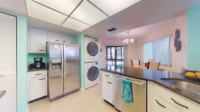 kitchen featuring white cabinetry, stacked washer and dryer, a chandelier, and appliances with stainless steel finishes