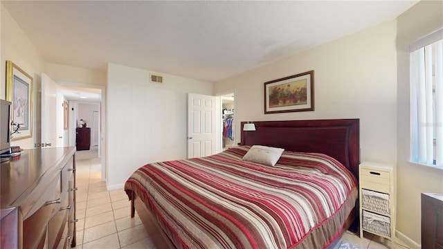 bedroom with a walk in closet, a closet, and light tile patterned floors