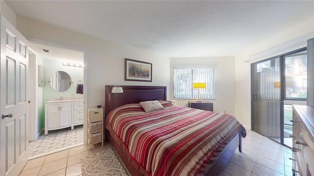 bedroom with light tile patterned flooring, sink, a textured ceiling, and connected bathroom