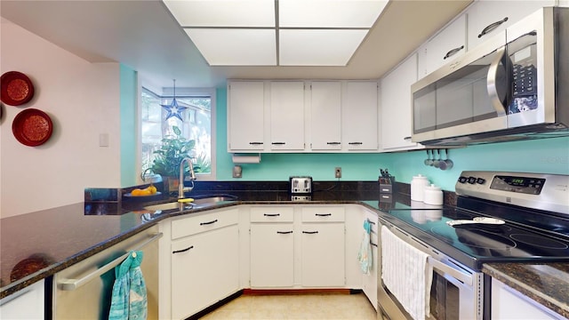 kitchen featuring white cabinets, dark stone countertops, sink, and appliances with stainless steel finishes