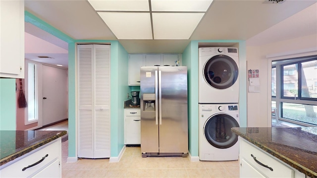 washroom with a healthy amount of sunlight, light tile patterned floors, and stacked washing maching and dryer