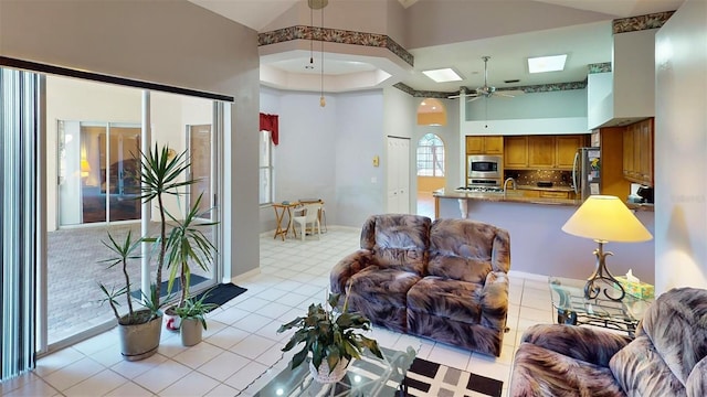 living room with ceiling fan, light tile patterned floors, and a high ceiling