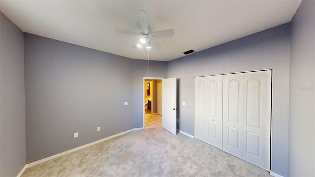 unfurnished bedroom featuring ceiling fan, light carpet, and a closet