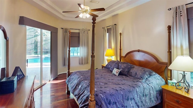 bedroom with a raised ceiling, access to exterior, ceiling fan, and dark hardwood / wood-style flooring