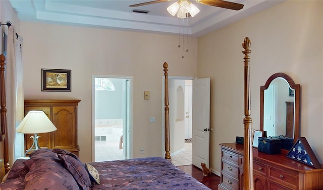 bedroom with a tray ceiling, ceiling fan, and light wood-type flooring