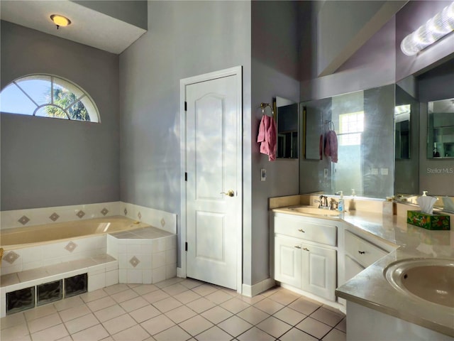 bathroom with tile patterned flooring, vanity, and tiled bath