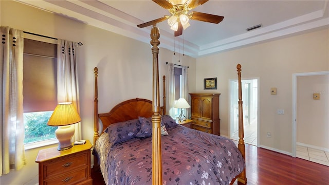 bedroom featuring hardwood / wood-style floors, ceiling fan, and a raised ceiling