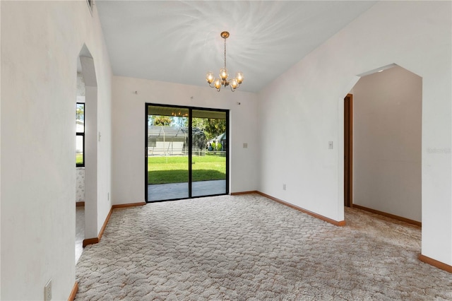 empty room featuring light colored carpet and an inviting chandelier