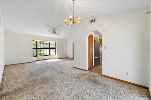 spare room featuring carpet and ceiling fan with notable chandelier