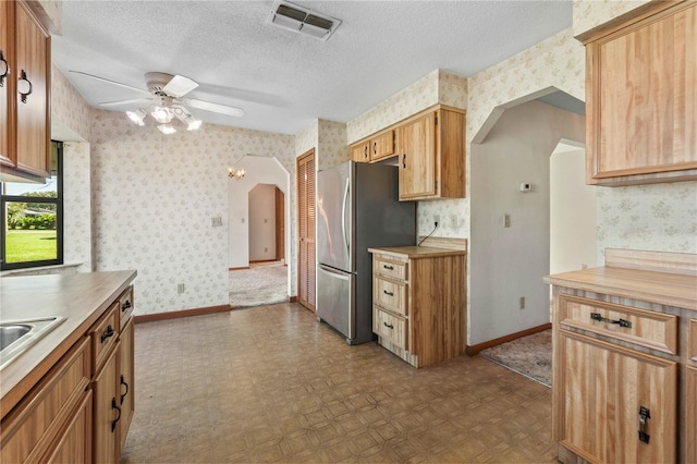 kitchen featuring stainless steel refrigerator, ceiling fan, and a textured ceiling