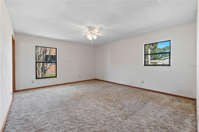 carpeted spare room with ceiling fan, a healthy amount of sunlight, and a textured ceiling