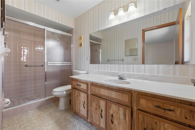 bathroom featuring tile patterned floors, vanity, toilet, and a shower with shower door