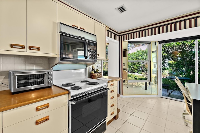 kitchen with range with electric stovetop, light tile patterned floors, and backsplash