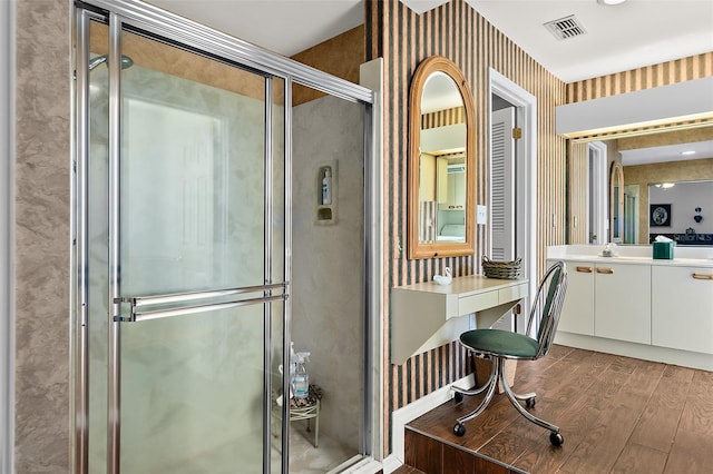 bathroom with hardwood / wood-style floors, vanity, and a shower with shower door