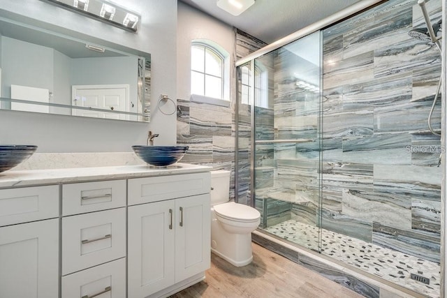 bathroom featuring hardwood / wood-style floors, vanity, toilet, and walk in shower