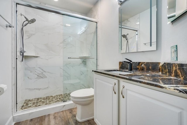 bathroom with hardwood / wood-style floors, vanity, toilet, and walk in shower