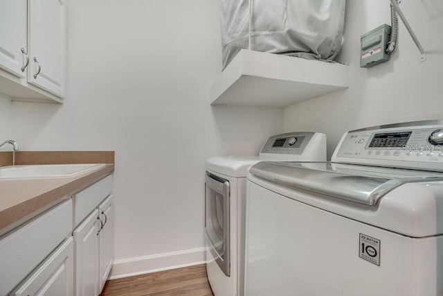 laundry room with hardwood / wood-style floors, washer and clothes dryer, cabinets, and sink