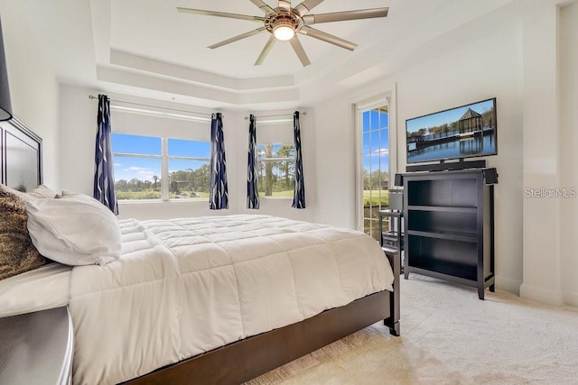 bedroom featuring a tray ceiling, ceiling fan, and light carpet