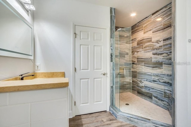 bathroom featuring hardwood / wood-style floors, vanity, and a shower with shower door