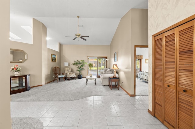 carpeted living room with ceiling fan and high vaulted ceiling