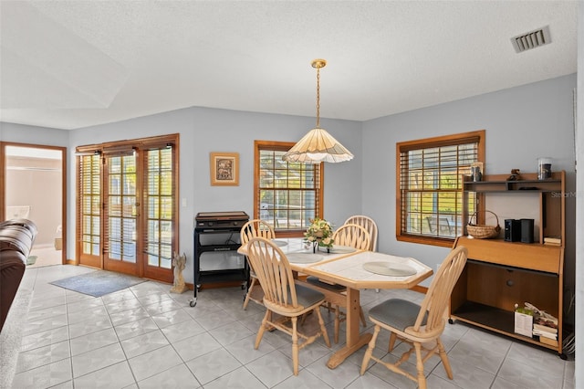 dining space featuring french doors, light tile patterned floors, and a textured ceiling