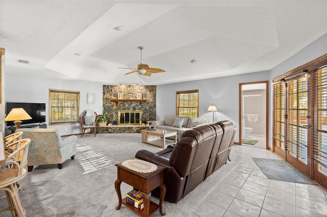 tiled living room with a tray ceiling, a wealth of natural light, and a fireplace