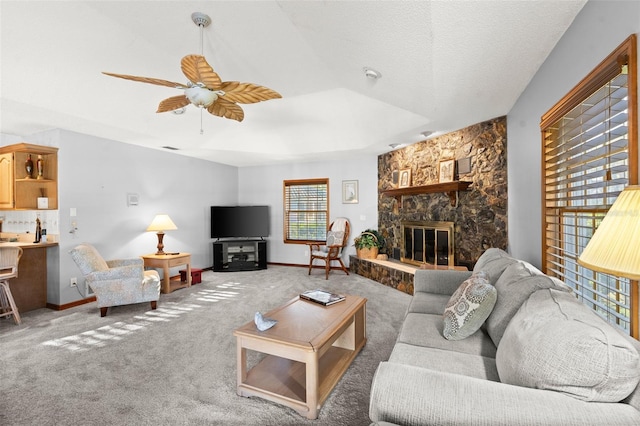 living room with ceiling fan, a fireplace, carpet, and a textured ceiling