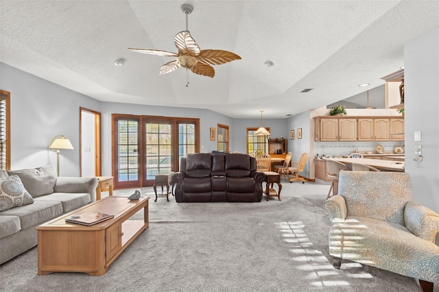 living room with a textured ceiling, ceiling fan, lofted ceiling, and light carpet