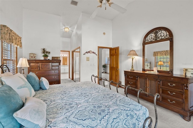 bedroom featuring light carpet, ensuite bathroom, high vaulted ceiling, and ceiling fan