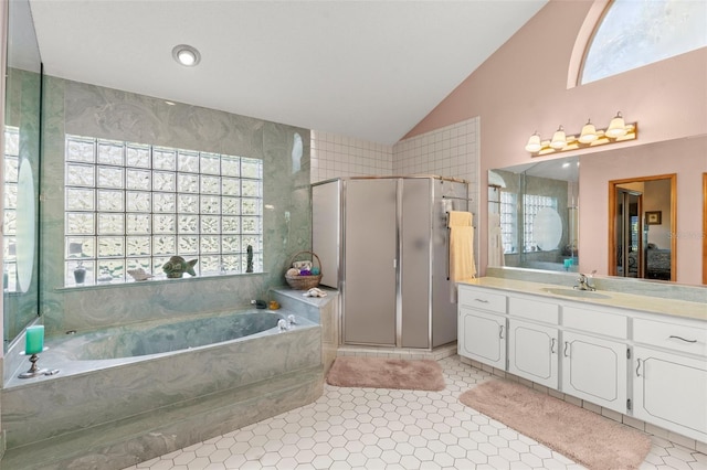 bathroom with tile patterned flooring, shower with separate bathtub, a wealth of natural light, and vaulted ceiling