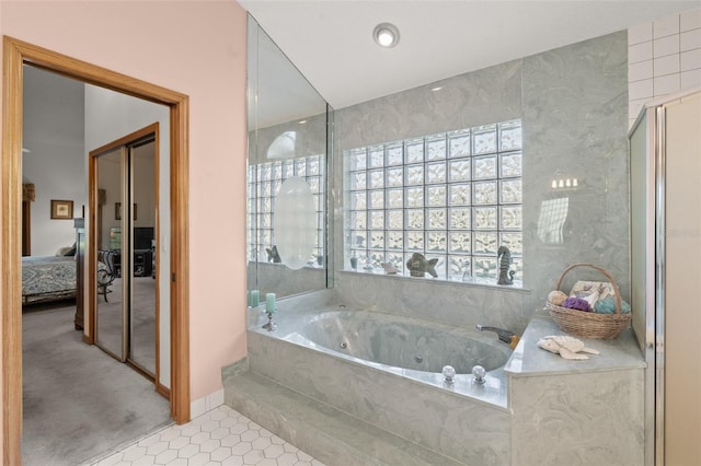 bathroom with a relaxing tiled tub and tile patterned floors