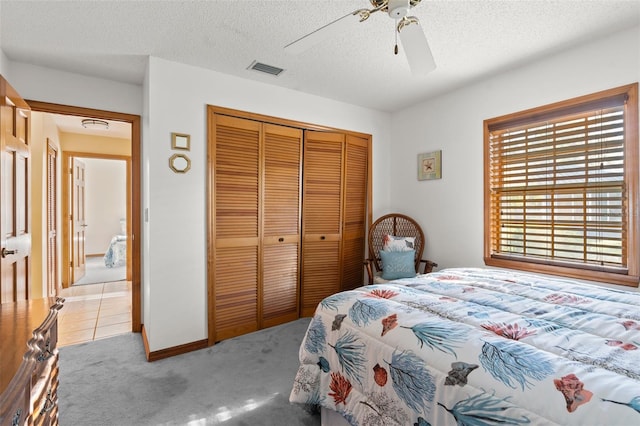 carpeted bedroom with ceiling fan, a closet, and a textured ceiling