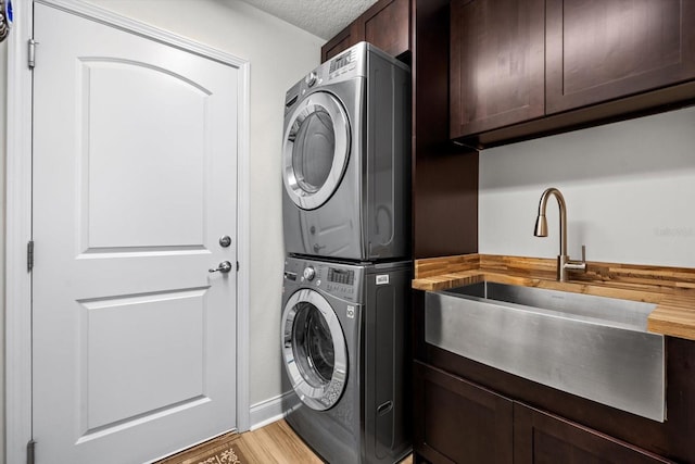6 Lindsay Dr, Palm Coast, FL 32137 - laundry room featuring stacked washer / drying machine, cabinet space, light wood finished floors, baseboards, and a textured ceiling