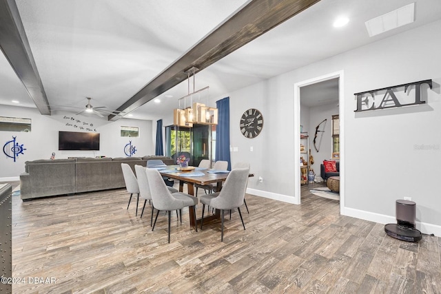 dining space with beamed ceiling, ceiling fan with notable chandelier, and hardwood / wood-style flooring