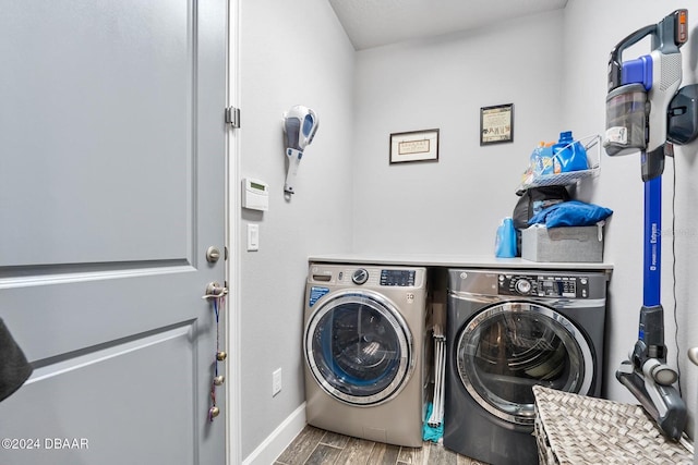 clothes washing area featuring washing machine and dryer and wood-type flooring