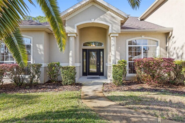 view of exterior entry featuring a lawn