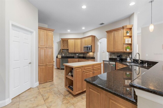 kitchen with backsplash, sink, wine cooler, appliances with stainless steel finishes, and decorative light fixtures