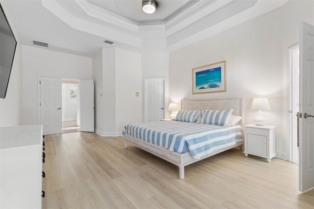 bedroom featuring a tray ceiling and light hardwood / wood-style flooring