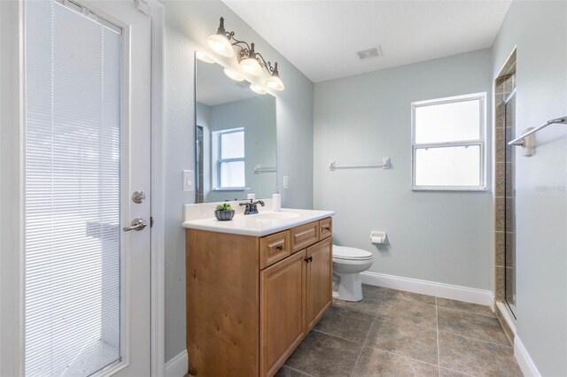 bathroom featuring tile patterned floors, vanity, toilet, and a shower with door