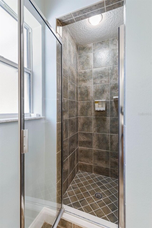 bathroom featuring a textured ceiling and a shower with shower door