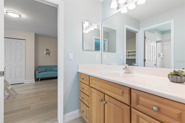 bathroom featuring vanity, hardwood / wood-style floors, a textured ceiling, and walk in shower