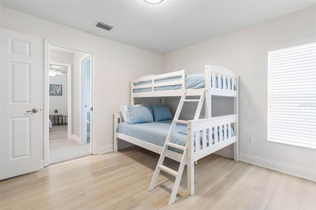 bedroom with light wood-type flooring, a textured ceiling, and multiple windows