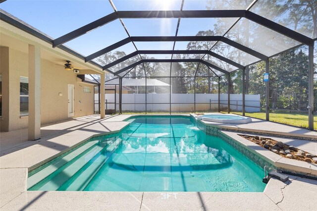 view of pool with an in ground hot tub, a patio, glass enclosure, and ceiling fan