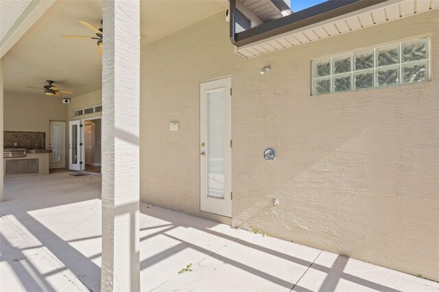 entrance to property featuring ceiling fan, a patio area, and an outdoor kitchen