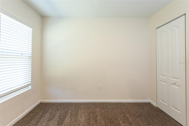 unfurnished bedroom featuring dark carpet and a closet