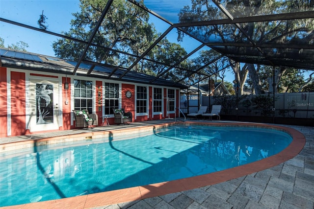 view of pool with glass enclosure and a patio