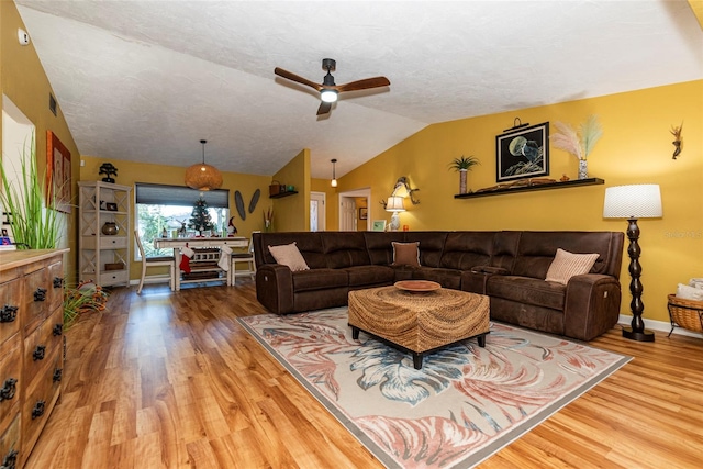 living room featuring a textured ceiling, hardwood / wood-style flooring, vaulted ceiling, and ceiling fan